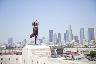 woman yoga pose on one leg in front of cityscape